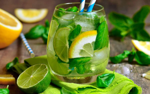 glass with lemonade, ice, and basil leaves