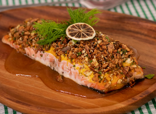 a salmon dish served with herbs spread on top of it